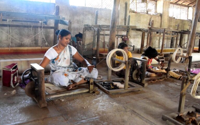 How are the spindle and Charkha different from spinning in factories?